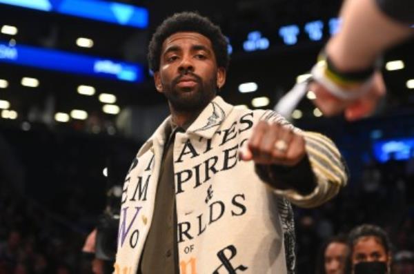 Kyrie Irving fist-bumps a fan while walking to his courtside seats at Barclays Center on Sunday, March 13, 2022.